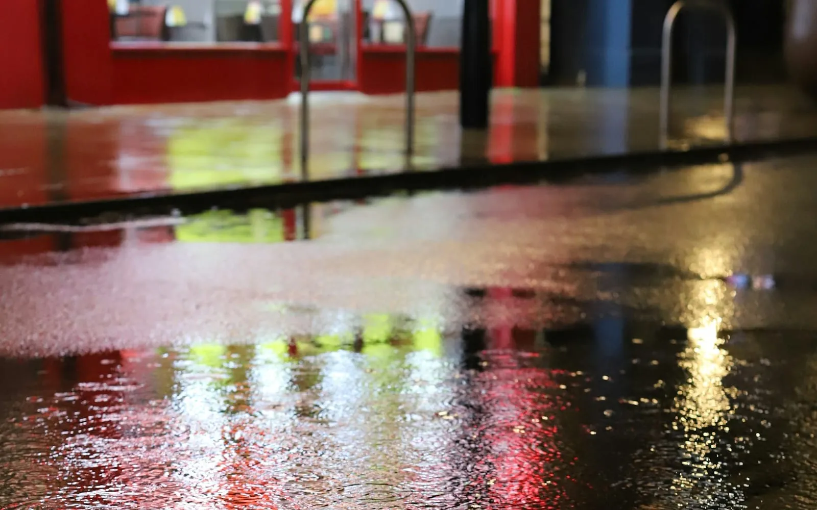 Colorful reflections across an empty rainy street at night