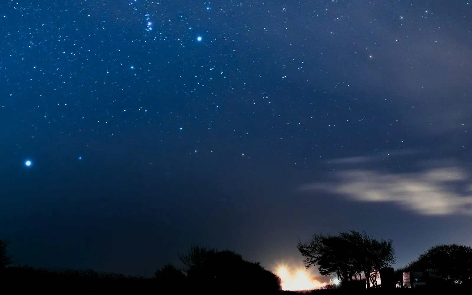 A star-filled night sky above a dark landscape