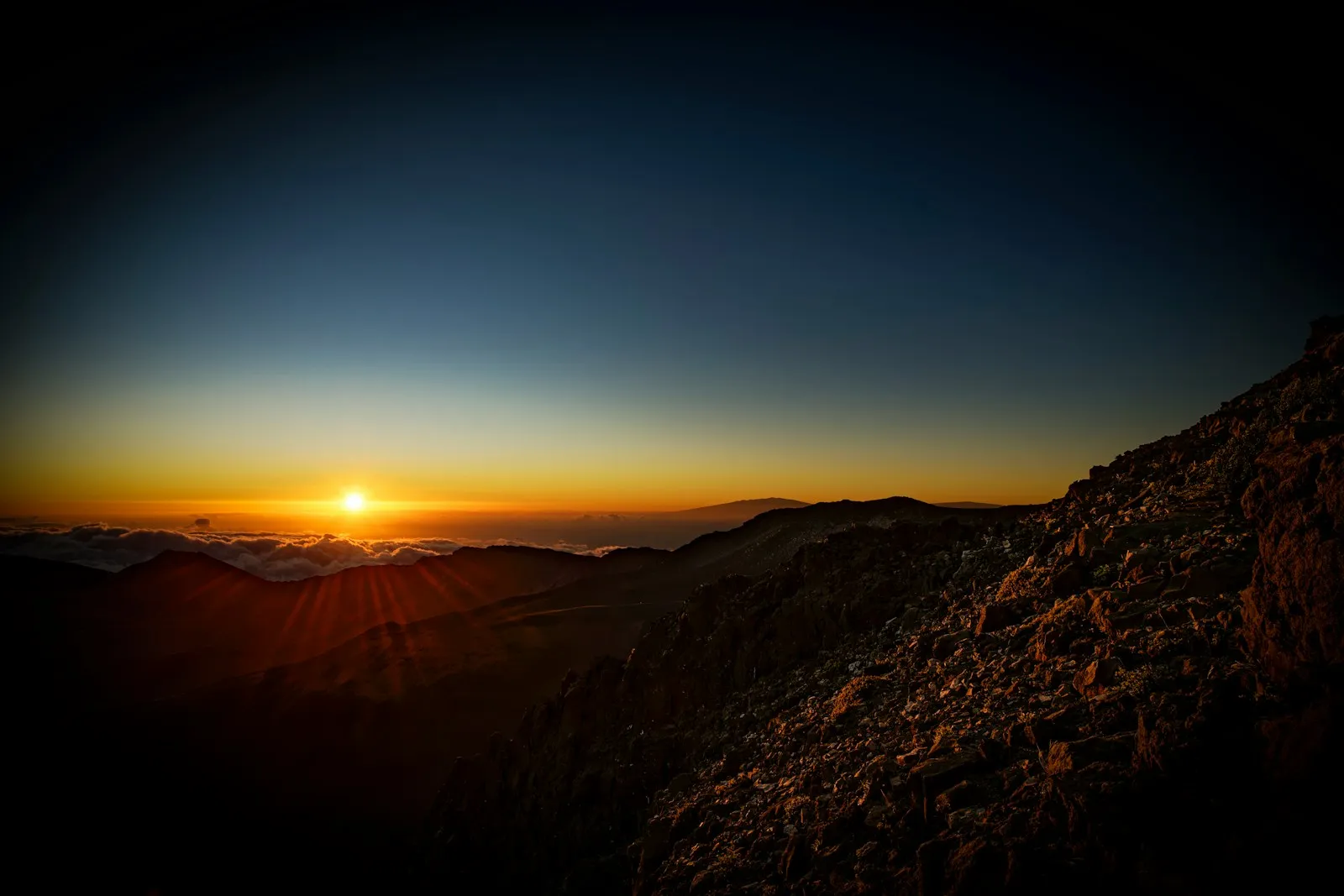 Sunrise above a mountain range and a layer of clouds