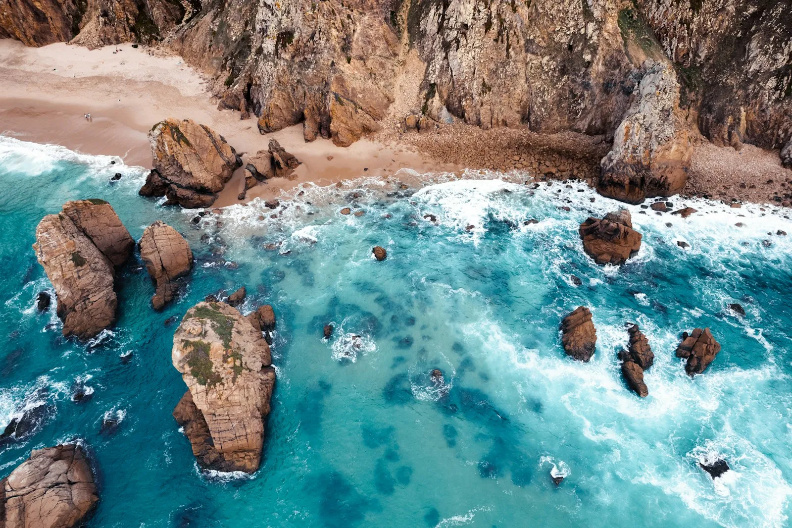 An aerial view of cliffs meeting deep blue water